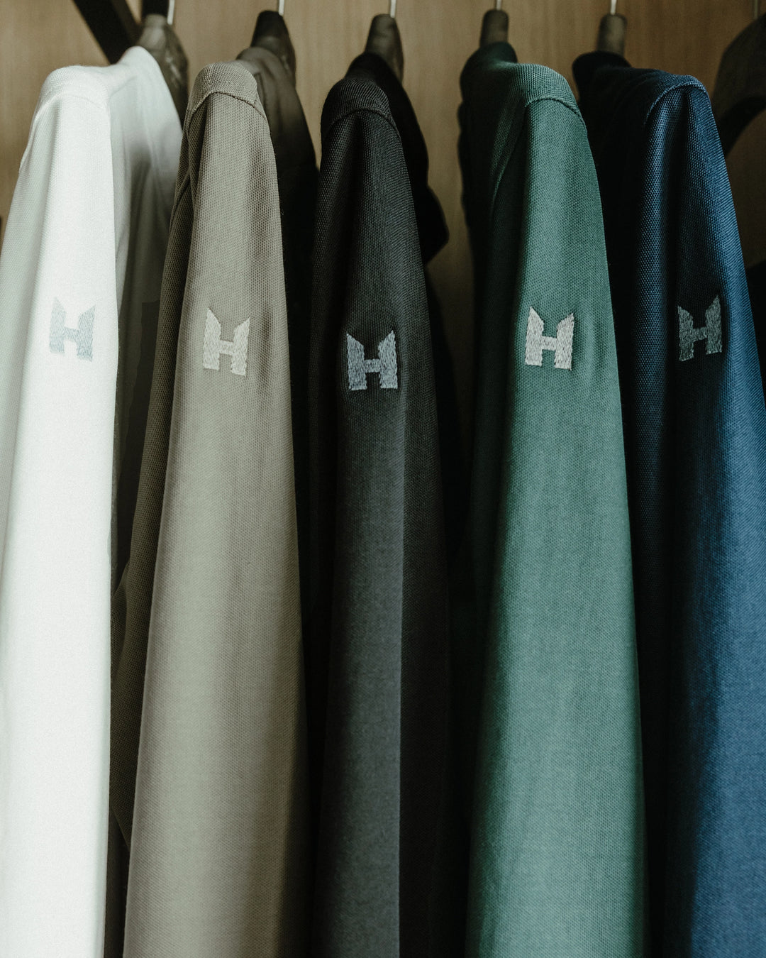 Hanging LE NOUVEAU CHEF service shirts and chef coats, showing the unbelievably comfortable fabrics, earth tone colors, and the prestigious logo on the sleeve.