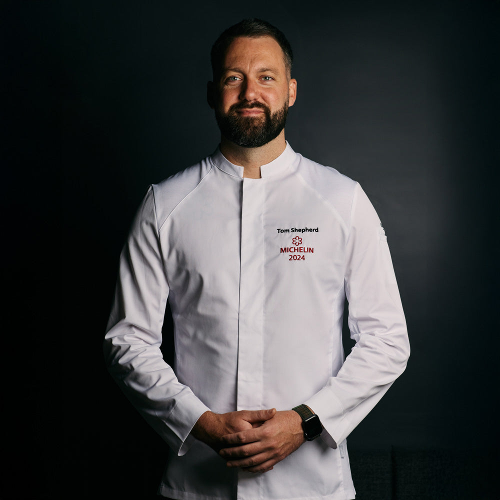 Michelin rated chef wearing a long-sleeve white French chef coat with breathable side vents, and a mandarin collar, designed for men.