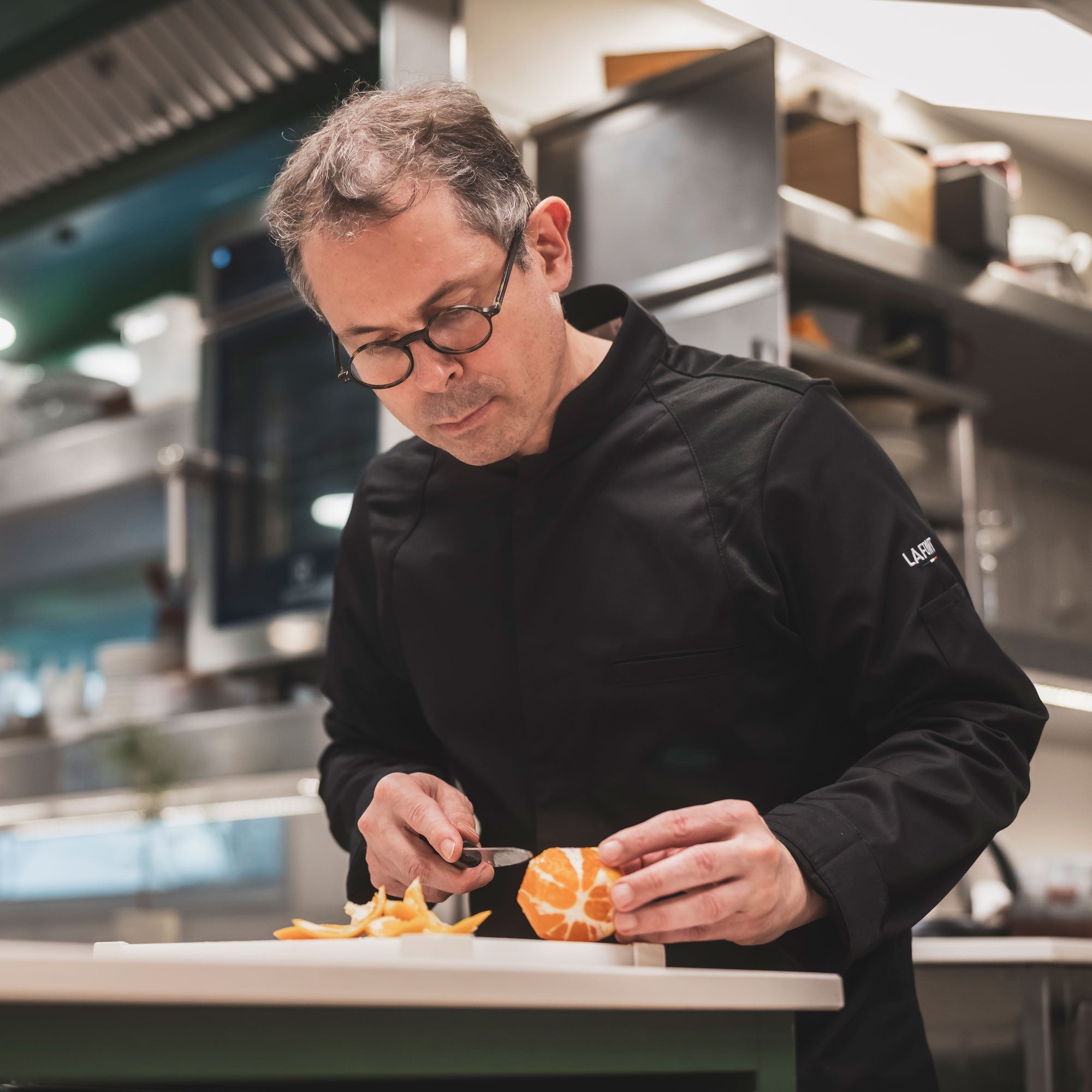 A cook wearing a black long sleeve chef jacket.