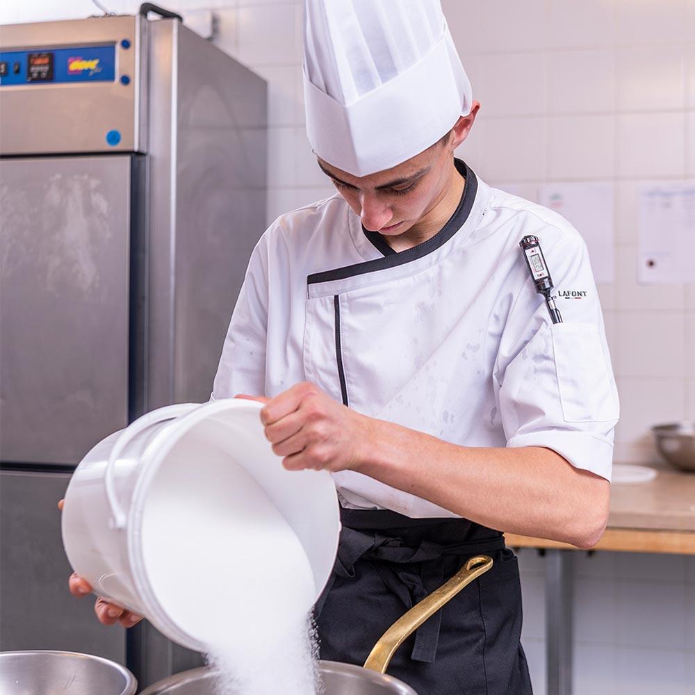 Lafont PARSLEY white with black contrast fabric, short sleeve men's chef coat, 1/4 view seen on a cook prepping in a professional kitchen.
