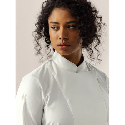 Person wearing a white chef's coat with a unique color against a neutral background