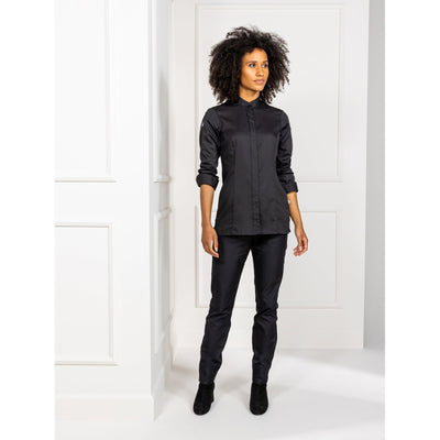Woman wearing a black chef's coat with hidden closure, stretch back panel and soft fabric. Elegant, comfortable kitchen jacket and black kitchen staff pants