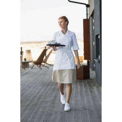 Waitress in a white apron and beige skirt holding a tray on a wooden deck.