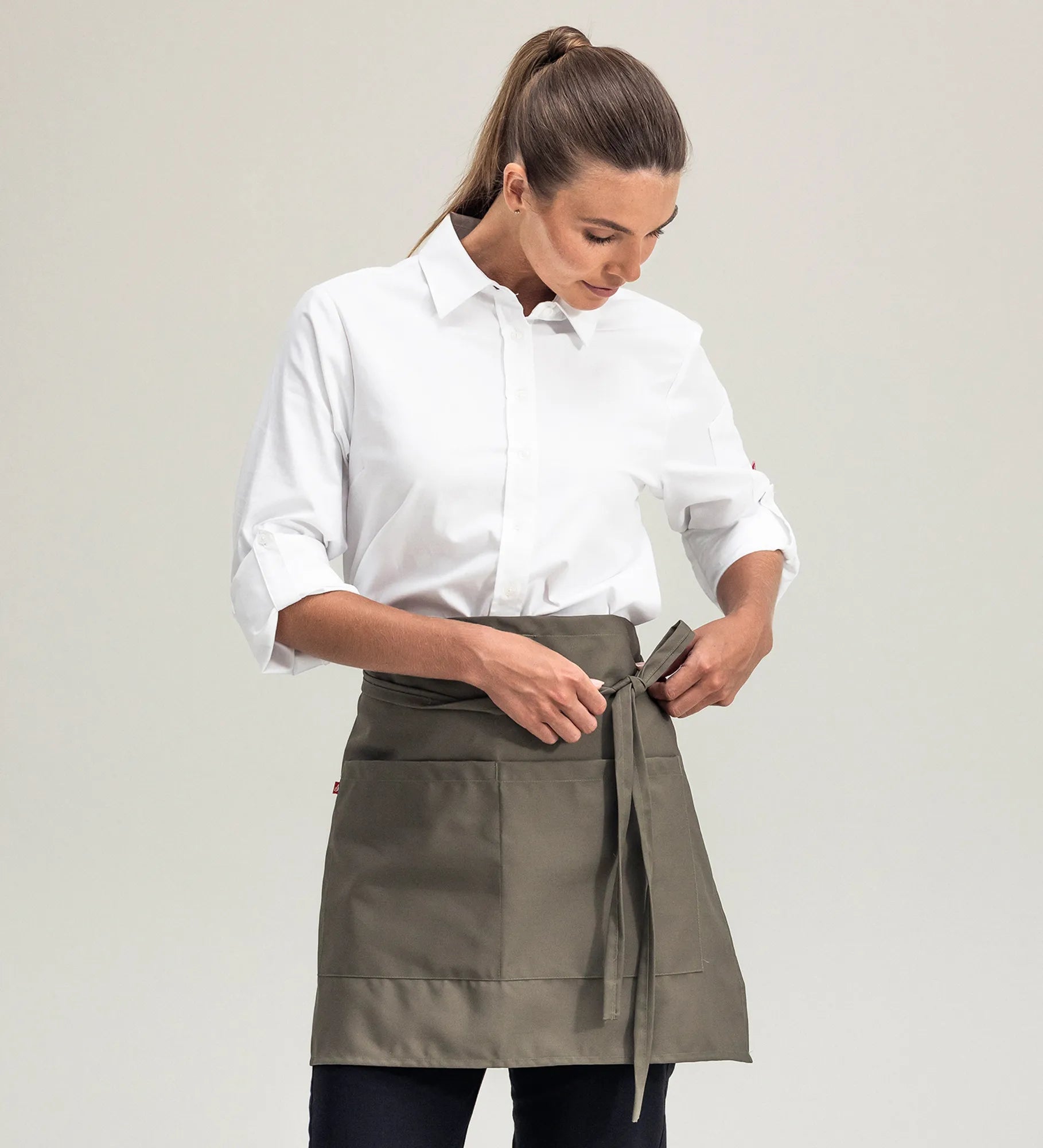 Head waitress putting on a olive green waist apron with pockets 