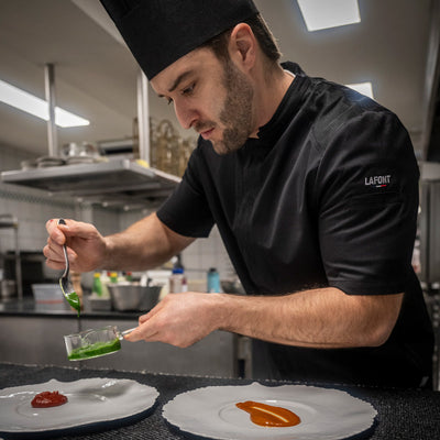 Chef plating in a short sleeve, chef jacket, and black fabric