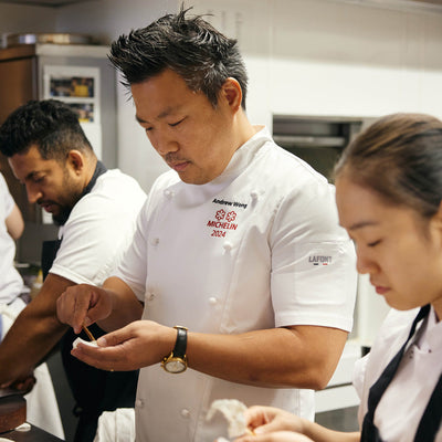 Michelin rated chef working in a busy kitchen wearing a Lafont Short sleeve double breasted chef jacket with custom embroidery