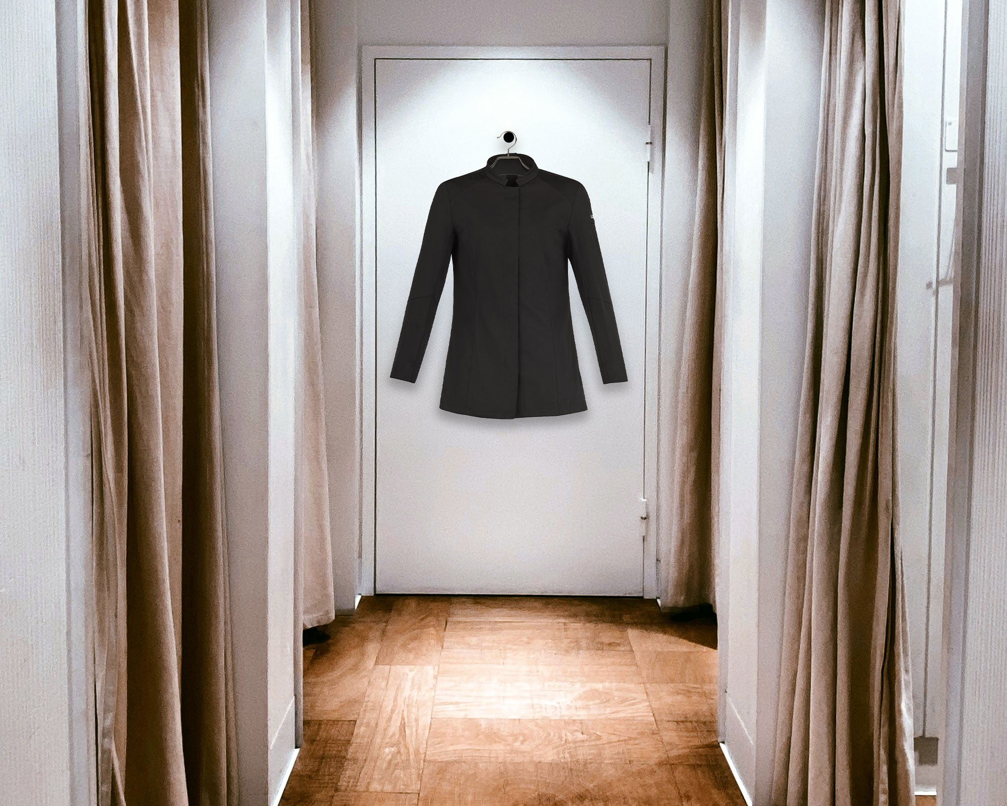 Long sleeve black chef, coat hanging in a fitting room. Find your perfect fit of European chef coats and serviceware available in the United States. When in doubt size up..